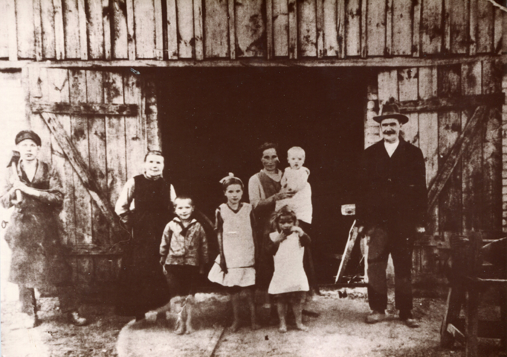 Schmiedemeister Emil Jeschke mit seiner Familie und dem Lehrling Otto Kitsch vor der Schmiede